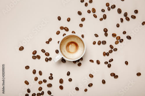 top view of coffee cup with foam on beige background with coffee grains