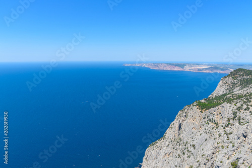 view of the Black Sea from the height of Mount Ayia, a cape on the southern coast of the Crimea, to the south-east of Balaclava. Sunny bright day with clouds on the sky. Spring view of the Crimea. © StockAleksey