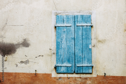 Volets en bois bleu fermés et façade enduit beige © PicsArt