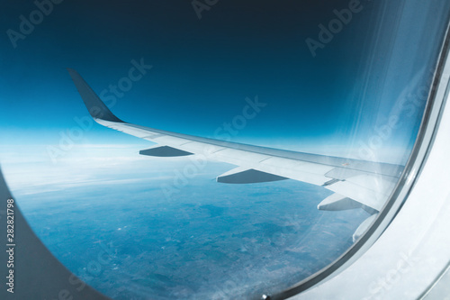 Wing of an airplane with deep blue sky and horizon view from the plane window. Traveling concept.