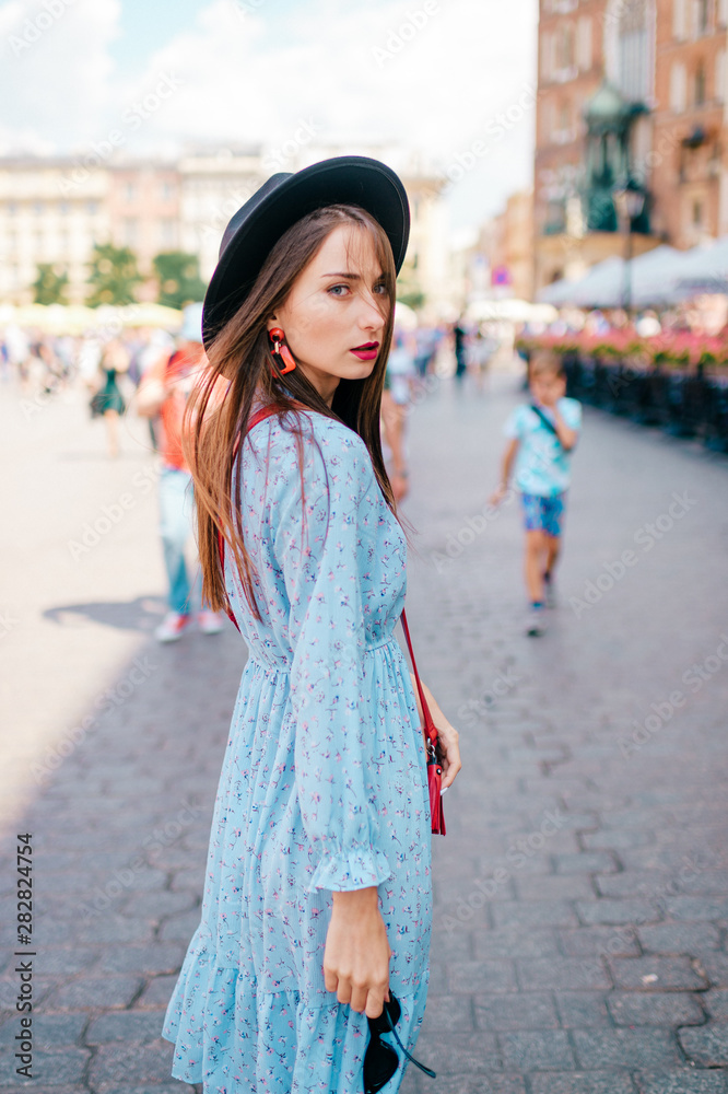 Young fashionable girl in blue dress looking back on street