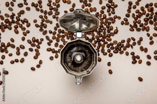 top view of opened metal coffee pot with fresh coffee near coffee beans on beige background