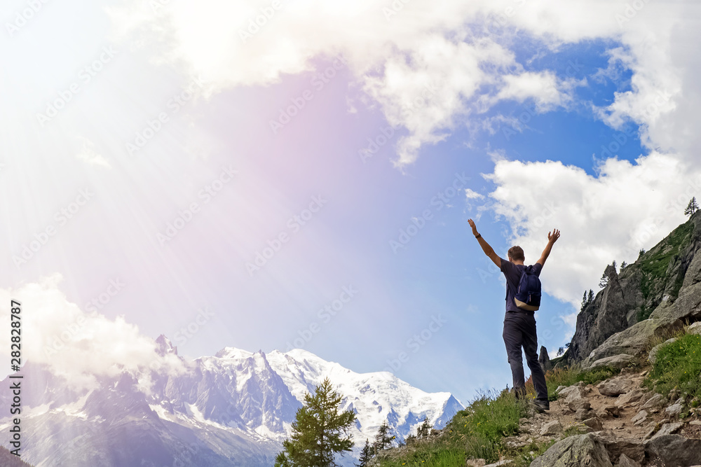 Young man in the mountains standing with his hands raised