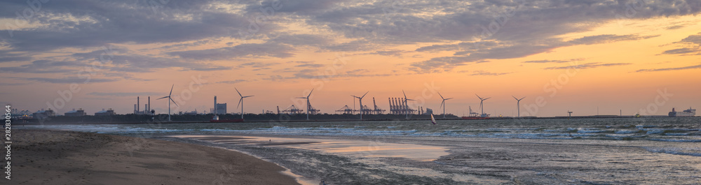 Panorama of the dutch coastline in Hoek van Holland at sunset. Container terminal and petrochemical industry on the horizon.