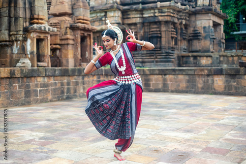 Indian classical dancer striking pose against the backdrop of  Mukteshvara Temple with sculptures in bhubaneswar, Odisha, India photo