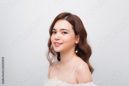 Beautiful smiling young asian woman with clean  fresh  glow  and perfect skin in white dress