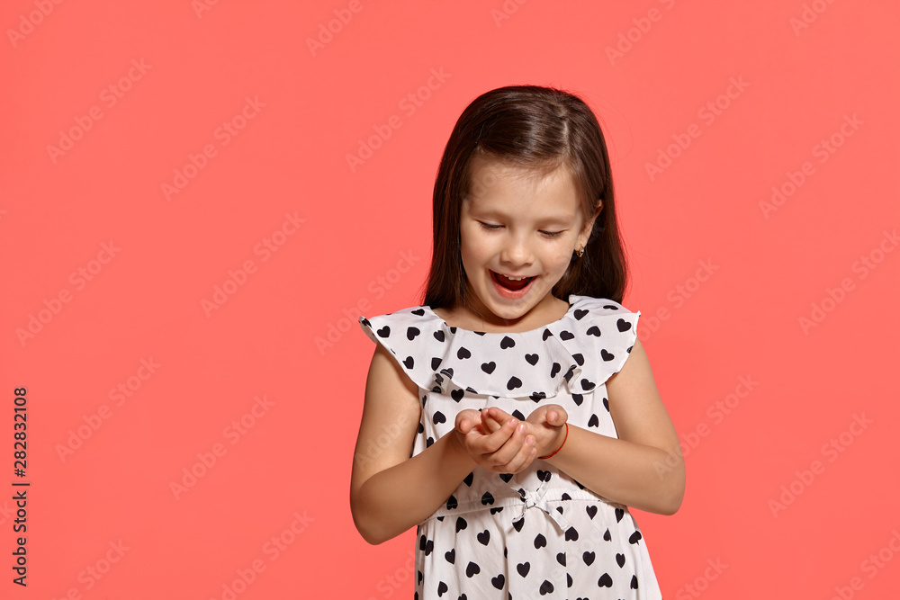 Close-up studio shot of beautiful brunette little girl posing against a pink background.