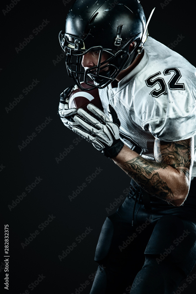 American football sportsman player in helmet isolated on black background. Sport and motivation wallpaper.