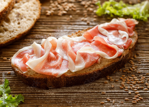 Ham sandwich, open faced sandwich with sourdough bread and ham on a wooden table, close up view
