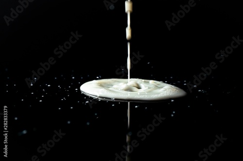 Milk spilled on black surface, closed up, selective focus