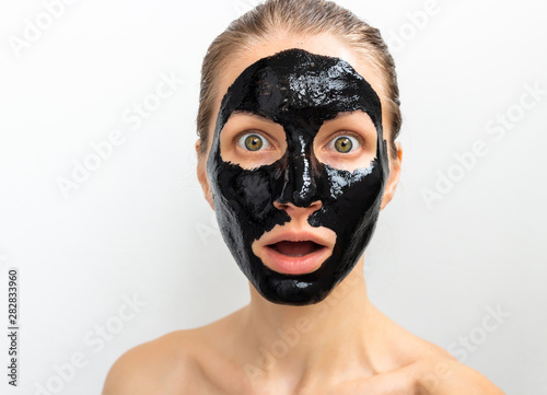 Humorous emotional young woman portrait with black mask on her face. Funny beauty spa treatment 