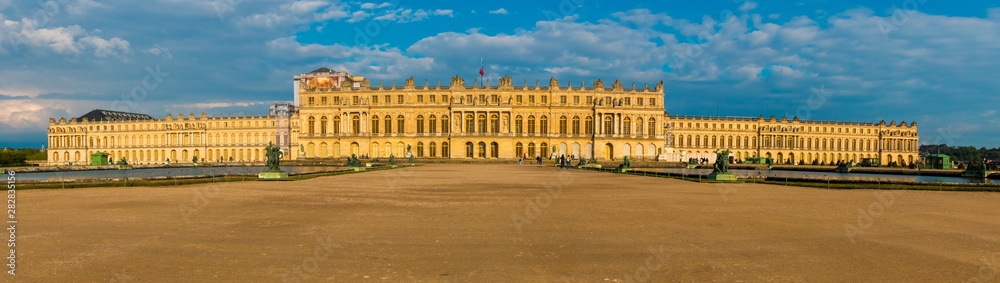 Great sunset panorama picture of the west facade of the famous Palace of Versailles from the Water Parterre with the two large rectangular pools and the gravel path in the middle. 