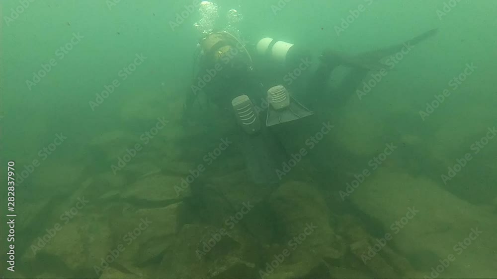scuba divers explore the rocky bottom in shallow water. young diver training. slow motion. dive into a mountain lake scuba divers explore the rocky bottom in shallow water. young diver training. slow motion. dive into a mountain lake