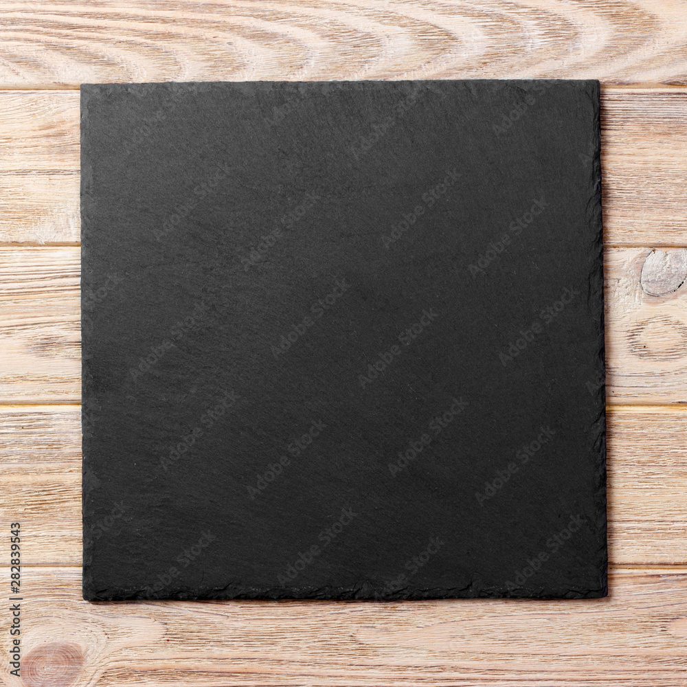 square plate on table. black dish on wooden background. copy space square plate on table. black dish on wooden background. copy space