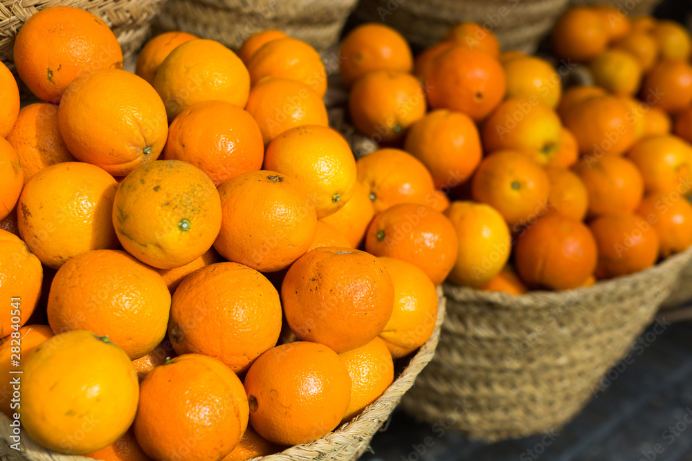 pile of juicy oranges in wicker baskets on market counter