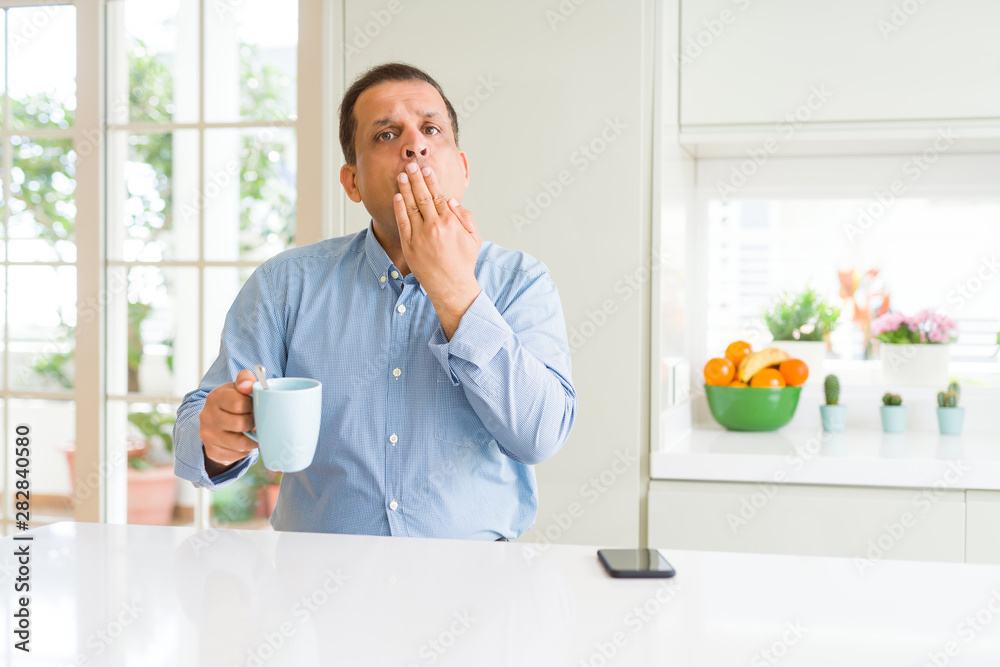 Middle age business man drinking coffee in the morning at home cover mouth with hand shocked with shame for mistake, expression of fear, scared in silence, secret concept Middle age business man drinking coffee in the morning at home cover mouth with hand shocked with shame for mistake, expression of fear, scared in silence, secret concept