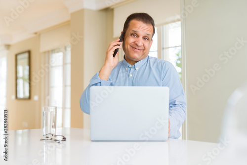 Middle age man working with laptop and using smartphone