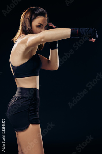 Athletic woman in boxing mittens is practicing karate in studio. © nazarovsergey
