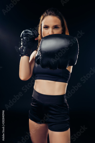 Athletic woman in boxing gloves is practicing karate in studio. © nazarovsergey