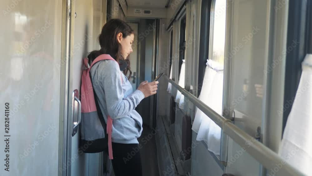 little girl walks on a train compartment car with a backpack and a smartphone. lifestyle travel transportation railroad concept. the girl in the train at the window corresponds the girl in the train little girl walks on a train compartment car with a backpack and a smartphone. lifestyle travel transportation railroad concept. the girl in the train at the window corresponds the girl in the train
