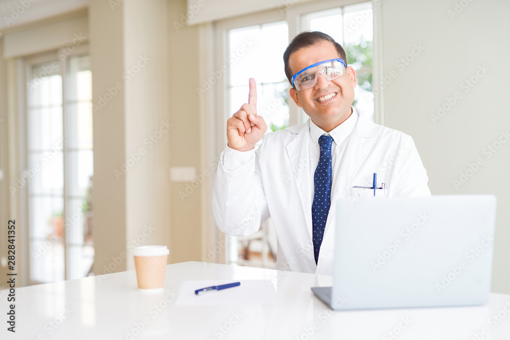 Middle age scientist man wearing professional glasses working using laptop surprised with an idea or question pointing finger with happy face, number one Middle age scientist man wearing professional glasses working using laptop surprised with an idea or question pointing finger with happy face, number one