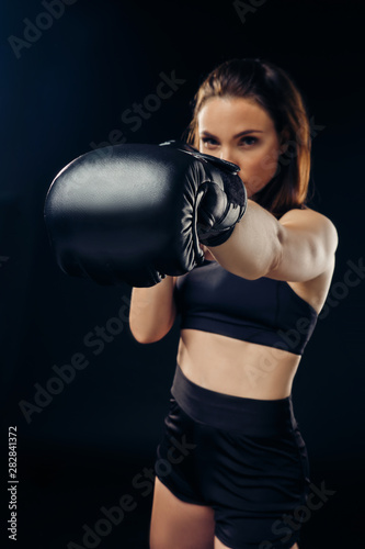 Athletic woman in boxing gloves is practicing karate in studio. © nazarovsergey