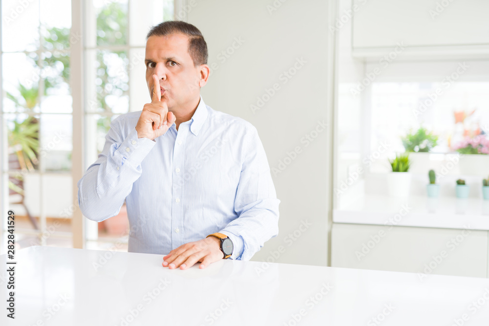 Middle age man sitting at home asking to be quiet with finger on lips. Silence and secret concept. Middle age man sitting at home asking to be quiet with finger on lips. Silence and secret concept.