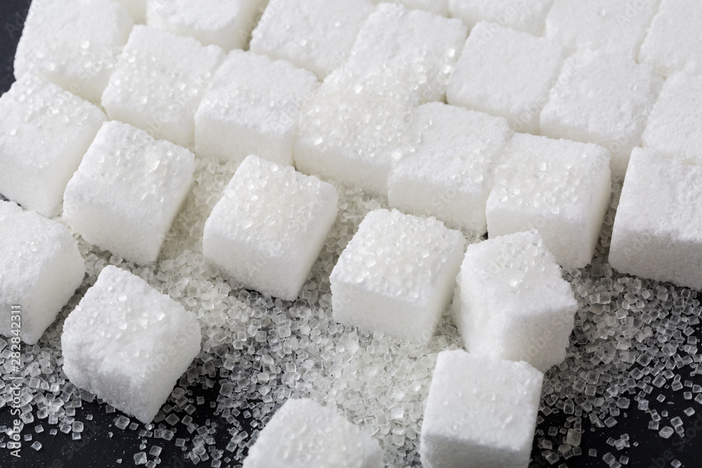 Closeup of granulated and sugar cube on black background