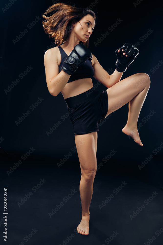Athletic woman in boxing gloves is practicing karate in studio. Athletic woman in boxing gloves is practicing karate in studio.