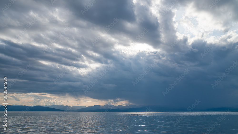 Evening cloudy sky over the sea and coastal mountains. Evening cloudy sky over the sea and coastal mountains.