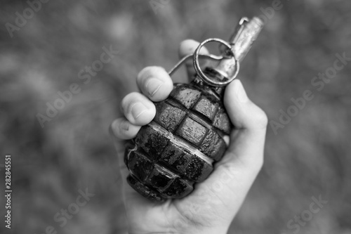 Fotografija Closeup top view of white kid hand holding real old grenade