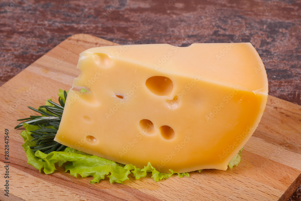 Maasdam cheese in the board served salad leaves Maasdam cheese in the board served salad leaves