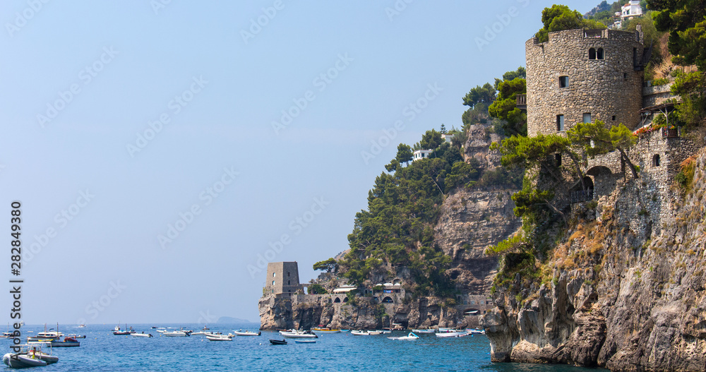 Old Castle Turrets overhanging the Tyrrhenian sea on the cliffs of Positano, in Italy (Amalfi Coast). Shot taken a sunny summer day, blue sky and sea, scattered with boats. – Image