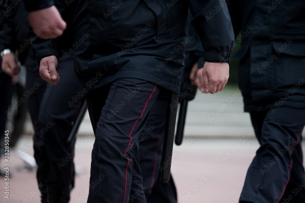 Russian police officers patrolling the street, rear view. Police officer holding a metal detector, security check. Russian police officers patrolling the street, rear view. Police officer holding a metal detector, security check.