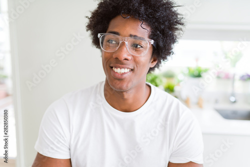 African American man wearing glasses smiling looking side and staring away thinking.