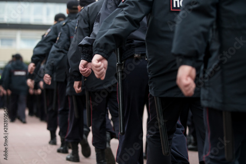 Russian police officers patrolling the street, rear view. Police officer holding a metal detector, security check.