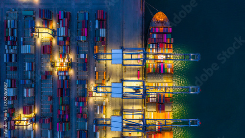 Container ship working at night, Business import export logistic and transportation of International by container ship in the open sea, Aerial view container ship loading and unloading at night. photo