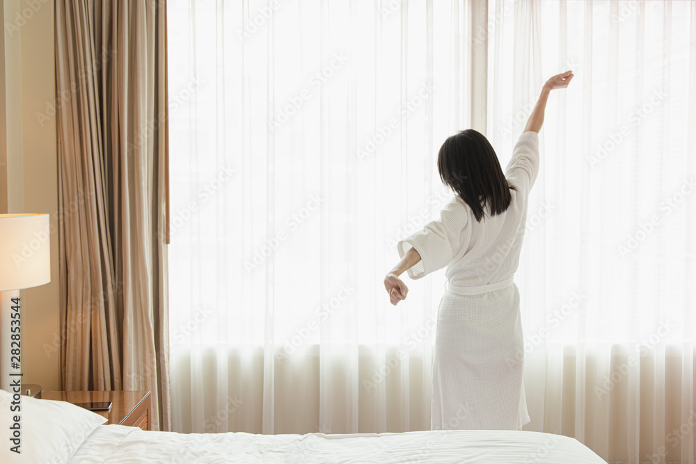 custom made wallpaper toronto digitalWoman stretching in bed after waking up, back view. Woman sitting near the big white window while stretching on bed after waking up with sunrise at morning, back view.