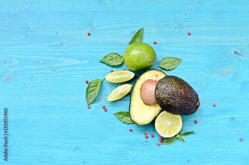 Top dish with raw food. Avocado, limes, lemons and mint on blue background. Copy space text.