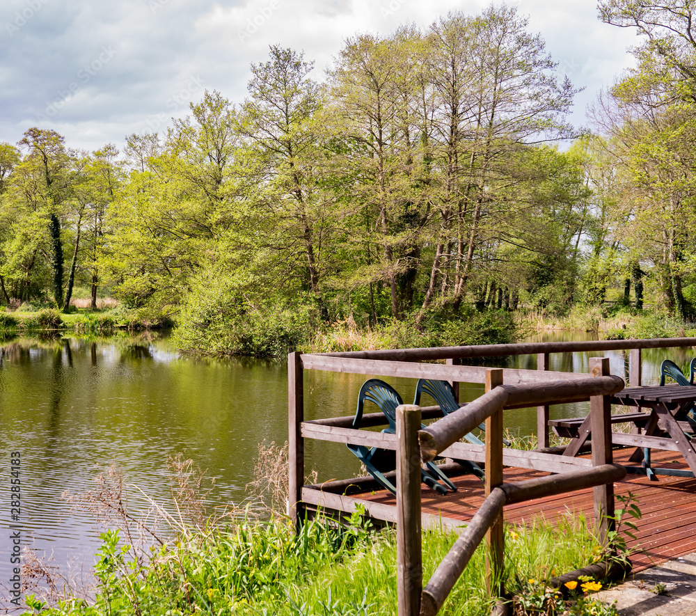 Wooden veranda and outside seating area with the view over a quiet lake in rural Norfolk