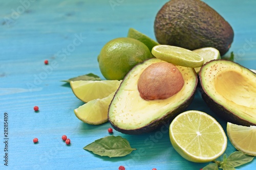 Concept of healthy food with half avocado, limes and mint on blue background and copy text.
