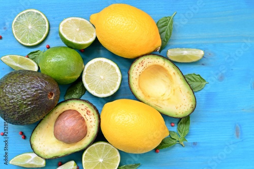 Top dish with raw food. Avocado, limes, lemons and mint on blue background.