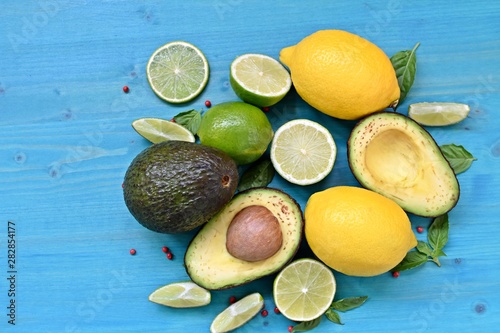 Top dish with raw food. Avocado, limes, lemons and mint on blue background. Copy space text.