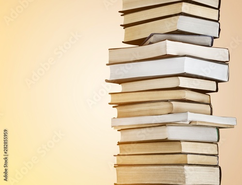 Collection of old books vertical stack on beige background