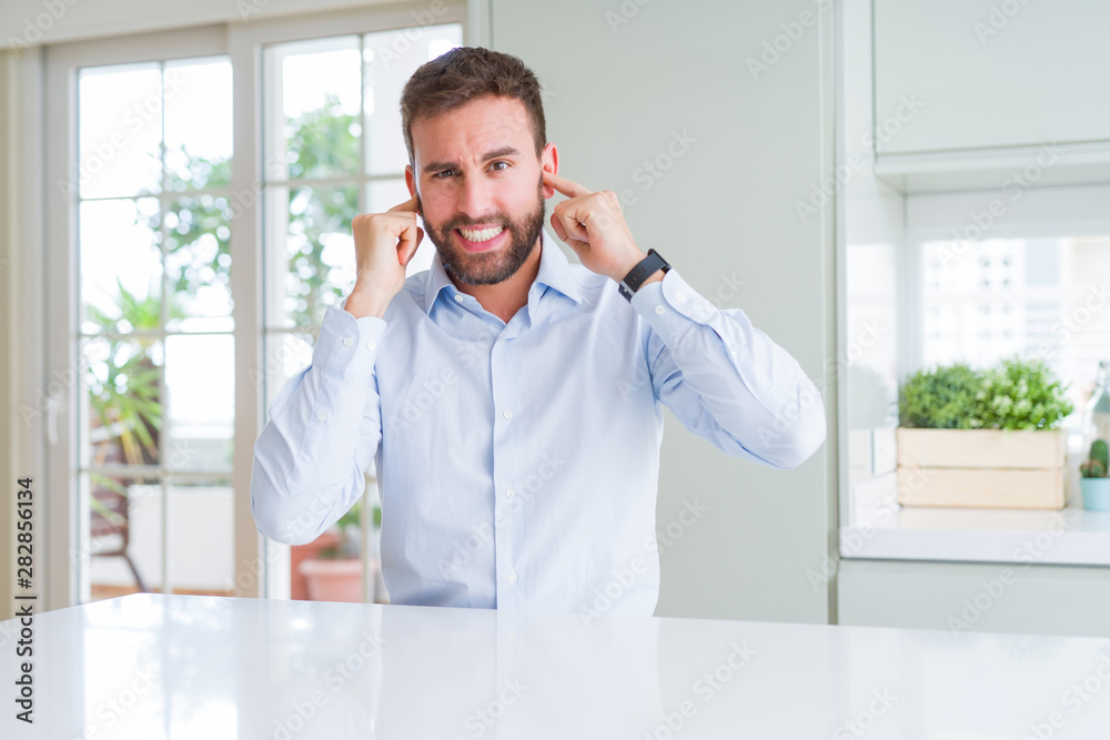 Handsome business man covering ears with fingers with annoyed expression for the noise of loud music. Deaf concept. Handsome business man covering ears with fingers with annoyed expression for the noise of loud music. Deaf concept.