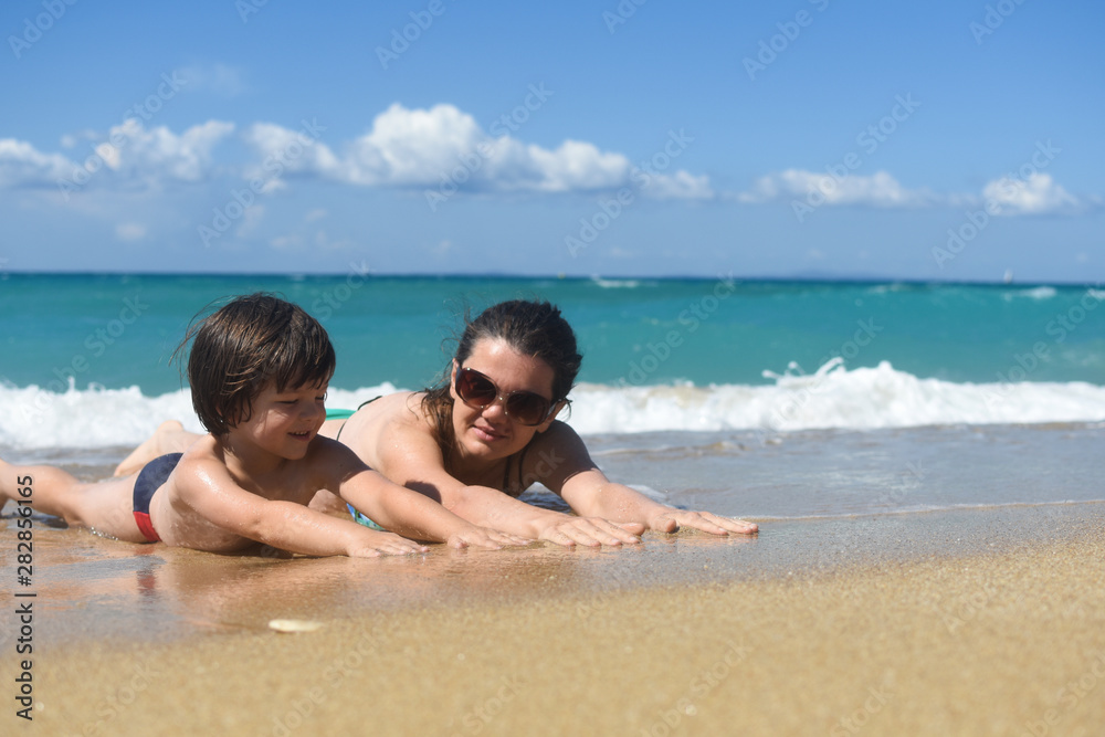 Mom with the small son On beach in the sea waves. Happy family enjoy at beach. Summer vacation, smiling and joy in waves Mom with the small son On beach in the sea waves. Happy family enjoy at beach. Summer vacation, smiling and joy in waves