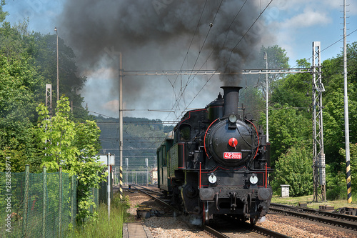 Fototapeta Naklejka Na Ścianę i Meble -  The steam locomotive departs from the station. Dense smoke rises from the chimney.