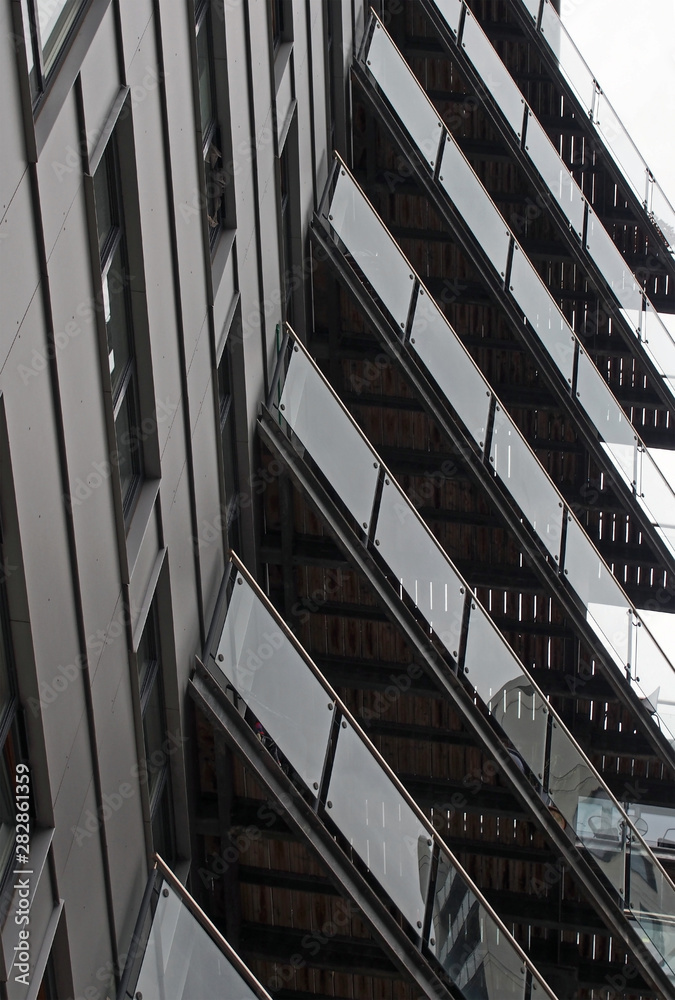 Obraz premium abstract detail view of a modern urban apartment building with black cladding and glass balconies reflecting other buildings