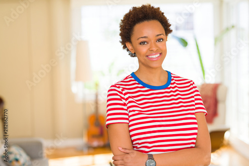 Beautiful young african american woman smiling confident to the camera showing teeth with crossed arms