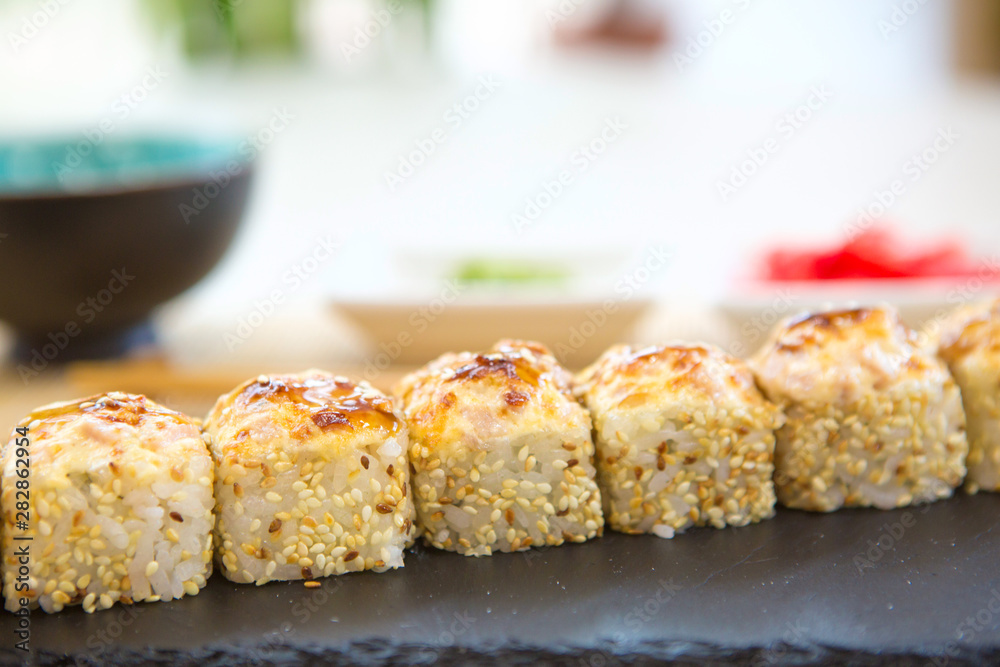 Japanese fried sushi rolls with salmon, tuna and shrimps on dark background. Healthy and tasty food.